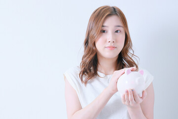 	豚の貯金箱を撫でる白色のＴシャツ姿の女性