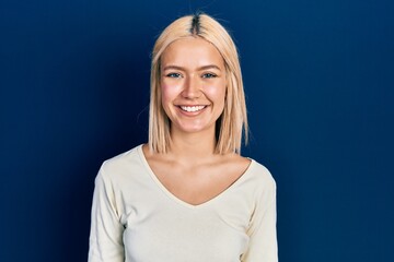 Beautiful blonde woman wearing casual sweater with a happy and cool smile on face. lucky person.