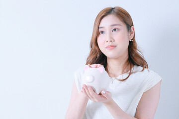 	豚の貯金箱を撫でながら遠くを見つめる女性
