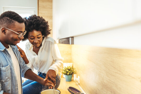Cooked with love. Cute laughing blonde frying something in skillet. Couple preparing food in kitchen. Couple preparing food in the kitchen of their cozy loft apartment