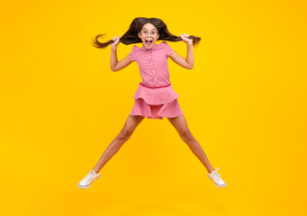 Amazed teenager. Full length overjoyed teenager kid girl 12 13 14 year in casual wear jumping old isolated on yellow background studio. Funny jump. Child in summer movement dress.