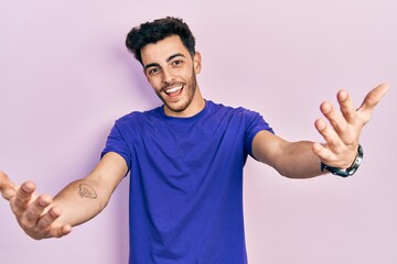 Young hispanic man wearing casual t shirt smiling cheerful offering hands giving assistance and acceptance.