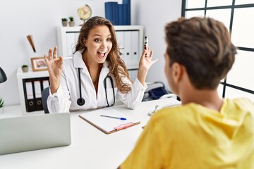 Young doctor woman showing electronic cigarette and normal cigarrete to patient celebrating crazy and amazed for success with open eyes screaming excited.