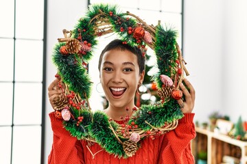 Young hispanic woman smiling confident holding christmas decoration at home