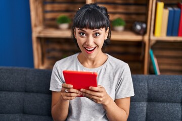 Young woman using touchpad sitting on sofa at home