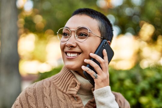 Young hispanic woman with short hair smiling happy speaking on the phone