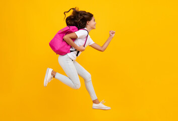 Fototapeta na wymiar Amazed teen girl. School girl in school uniform with school bag. Schoolchild teenager hold backpack on yellow isolated background. Run and jump. Excited expression, cheerful and glad.