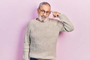 Handsome senior man with beard wearing casual sweater and glasses smiling pointing to head with one...