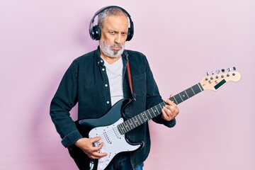 Handsome senior man with beard playing electric guitar depressed and worry for distress, crying angry and afraid. sad expression.