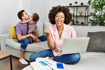 Mother of interracial family working using computer laptop at home very happy and excited doing...