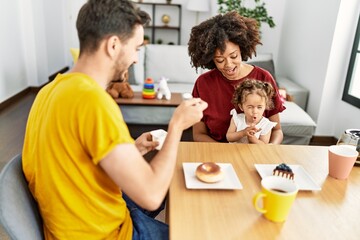 Couple and daughter having breakfast sitting on table at home