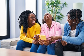 African american friends using smartphone sitting on sofa at home