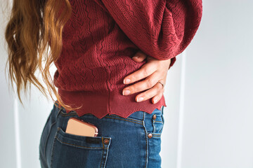 Woman with long hair with mobile phone in the back pocket of her jeans. White background - Powered by Adobe