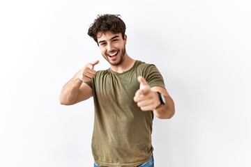 Naklejka premium Hispanic man standing over isolated white background pointing fingers to camera with happy and funny face. good energy and vibes.