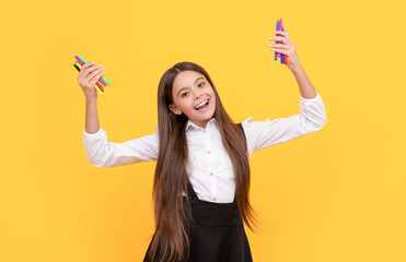 Happy school girl hold felt-tips yellow background, artistic education