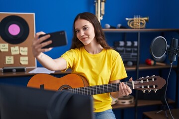 Fototapeta na wymiar Young woman musician make selfie by smartphone holding classical guitar at music studio