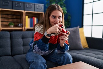 Young woman playing video game sitting on sofa at home