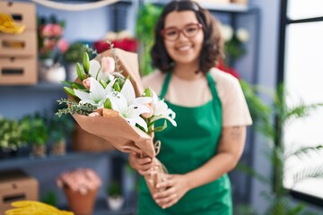 Young woman florist holding bouquet of flowers at florist
