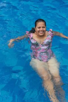 Older Woman Relaxing In The Pool During The Summer.