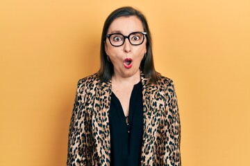 Middle age hispanic woman wearing business clothes and glasses scared and amazed with open mouth...