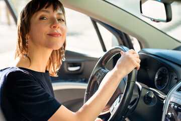 Woman sitting in a car behind the wheel and smiling