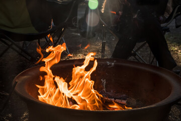 Campfire burning in a firepit . People sitting around. Camping life. Outdoor recreation.