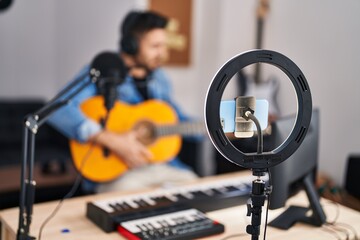 Young hispanic man musician having online guitar lesson at music studio