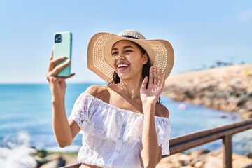 Young brazilian woman taking a selfie photo with smartphone outdoors looking positive and happy standing and smiling with a confident smile showing teeth