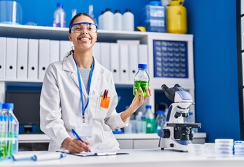 Young african american woman scientist measuring liquid at laboratory