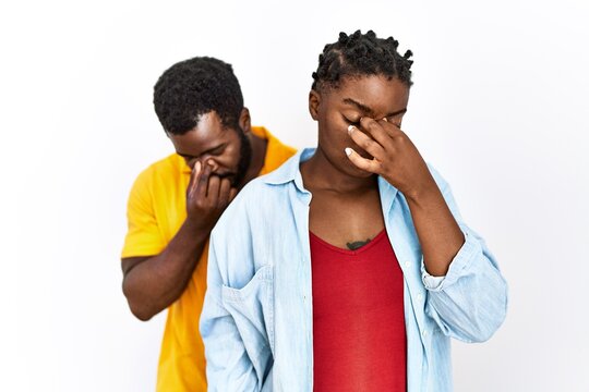 Young african american couple wearing casual clothes tired rubbing nose and eyes feeling fatigue and headache. stress and frustration concept.