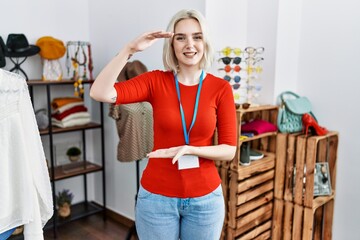 Young caucasian woman working as manager at retail boutique gesturing with hands showing big and large size sign, measure symbol. smiling looking at the camera. measuring concept.