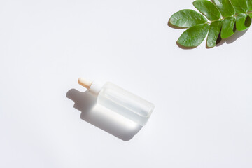 Cosmetic bottles with green leaf on white background