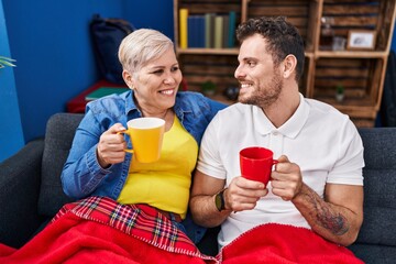 Mother and son drinking coffee sitting on sofa at home