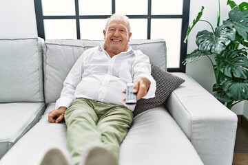 Senior man watching movie sitting on sofa at home