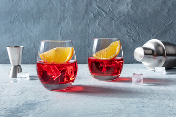 Campari aperitif with fresh orange slices, a jigger and a shaker. A summer cocktail with ice