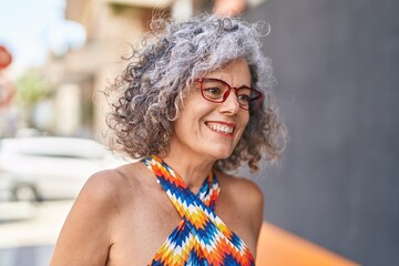 Middle age grey-haired woman smiling confident wearing glasses at street