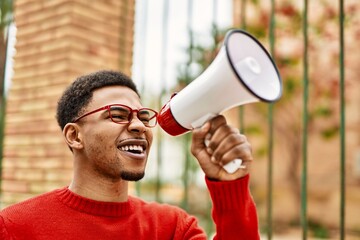 Handsome african american young man outdoors screaming through megaphone