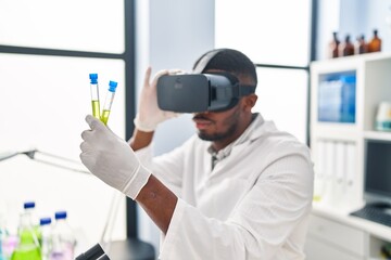 Young african american man wearing scientist uniform using virtual reality glasses at laboratory