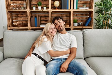 Young beautiful couple sitting on the sofa and hugging at home.