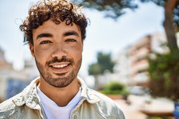 Handsome hispanic man with beard smiling happy outdoors on a sunny day