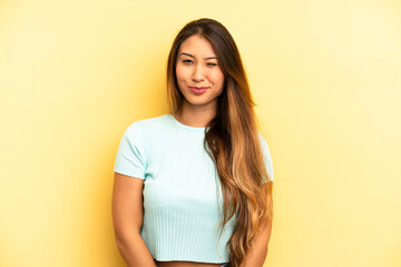 asian pretty woman looking happy and friendly, smiling and winking an eye at you with a positive...