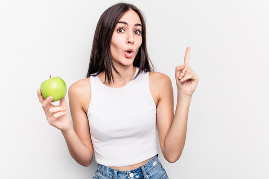 Young caucasian woman holding an apple isolated on white background having an idea, inspiration concept.
