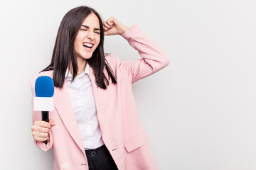 Fototapeta premium Young TV presenter caucasian woman isolated on white background raising fist after a victory, winner concept.