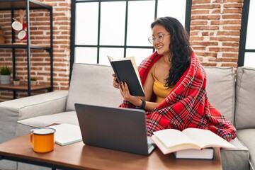 Young chinese woman studying sitting on sofa at home