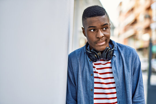 Young african american man with serious expression using headphones at the city.