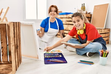 Obraz premium Two artist student women smiling happy painting sitting on the floor at art school.