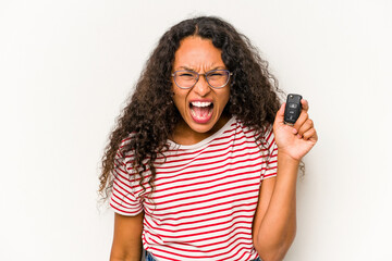 Young hispanic woman holding car keys isolated on white background screaming very angry and aggressive.