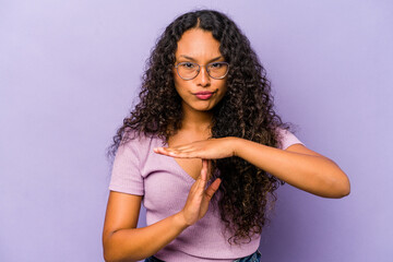 Young hispanic woman isolated on purple background showing a timeout gesture.