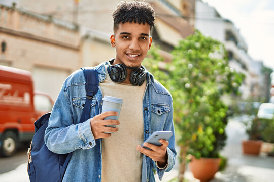 Hispanic young man using smartphone drinking a coffee at the street