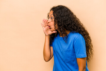 Young hispanic woman isolated on beige background is saying a secret hot braking news and looking aside